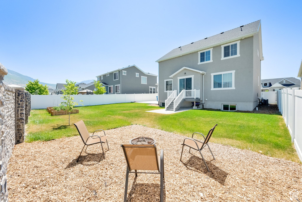 Rear view of house featuring an outdoor fire pit, a fenced backyard, and stucco siding