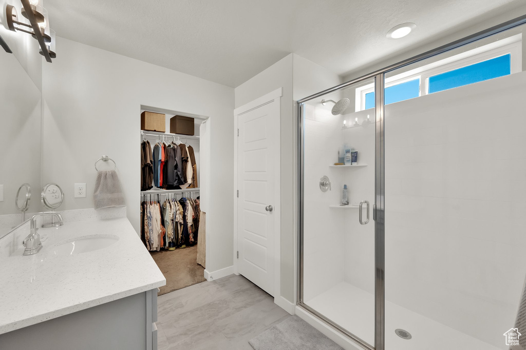 Bathroom with vanity, a stall shower, a spacious closet, and finished concrete flooring