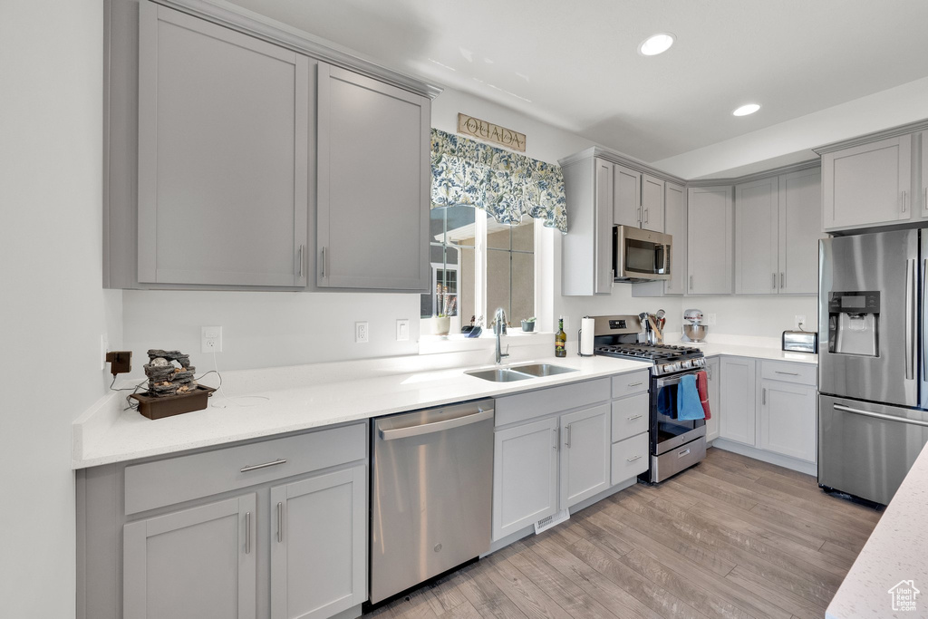 Kitchen featuring appliances with stainless steel finishes, gray cabinets, recessed lighting, and light wood-type flooring