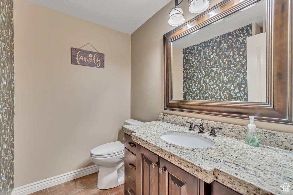 Half bath with tile patterned floors and vanity