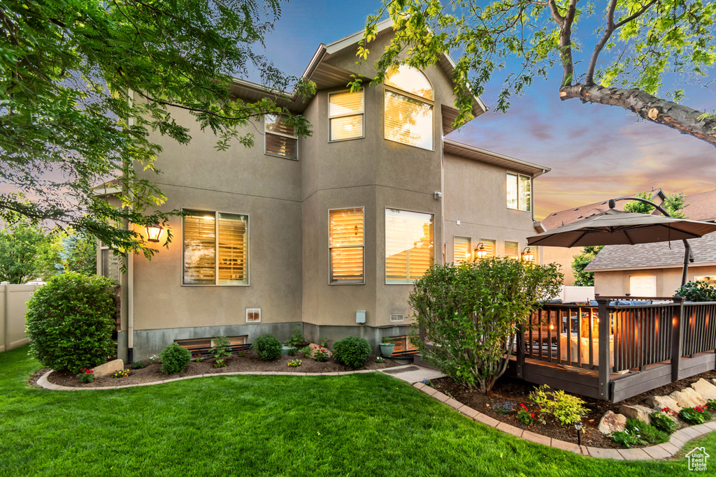Rear view of house featuring stucco siding, a deck, and a lawn