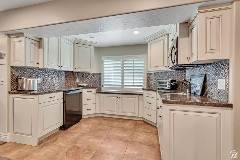 Kitchen featuring dishwasher, stainless steel microwave, tasteful backsplash, dark stone countertops, and recessed lighting