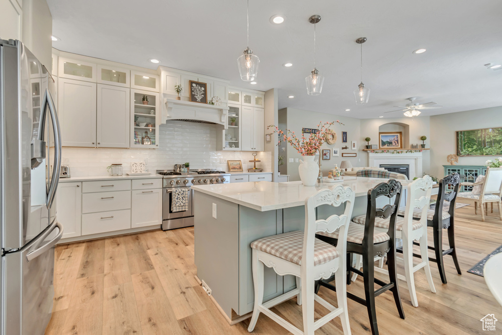 Kitchen with stainless steel appliances, light wood-style flooring, a ceiling fan, light countertops, and tasteful backsplash