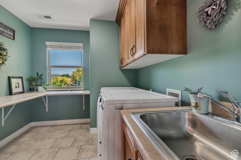 Washroom featuring cabinet space, washer and dryer, and light tile patterned floors