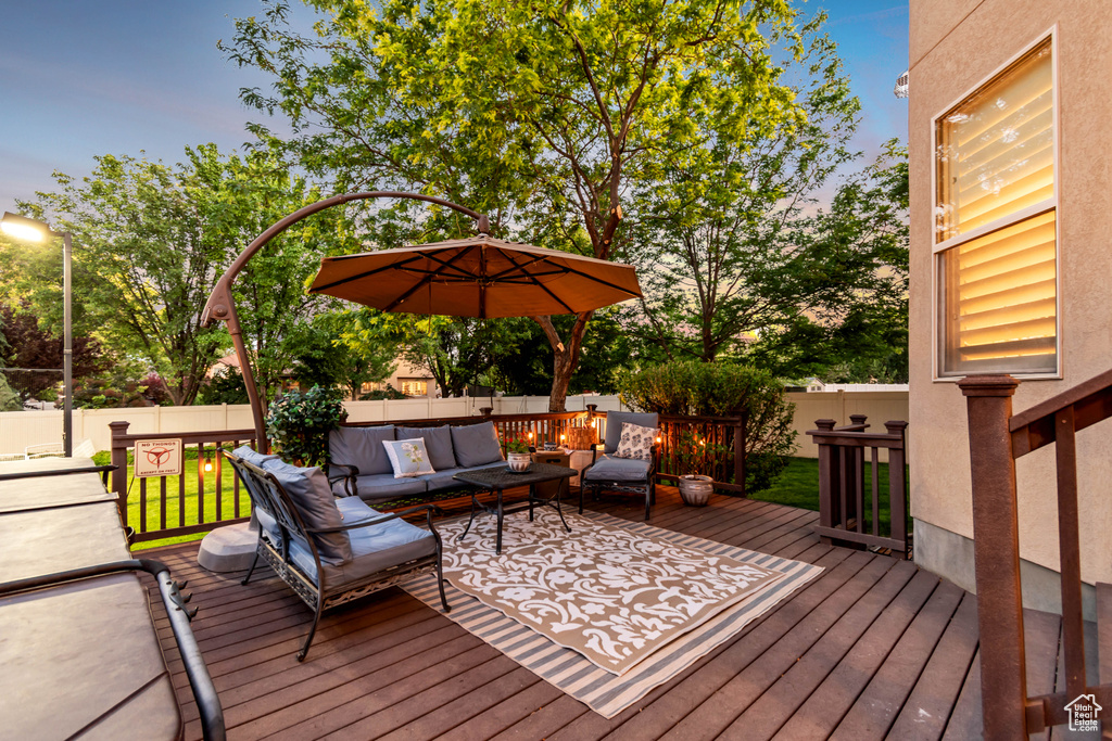 Deck at dusk with an outdoor hangout area and a fenced backyard