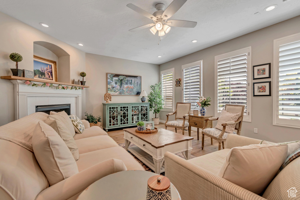 Living room featuring wood finished floors, ceiling fan, a fireplace, and recessed lighting