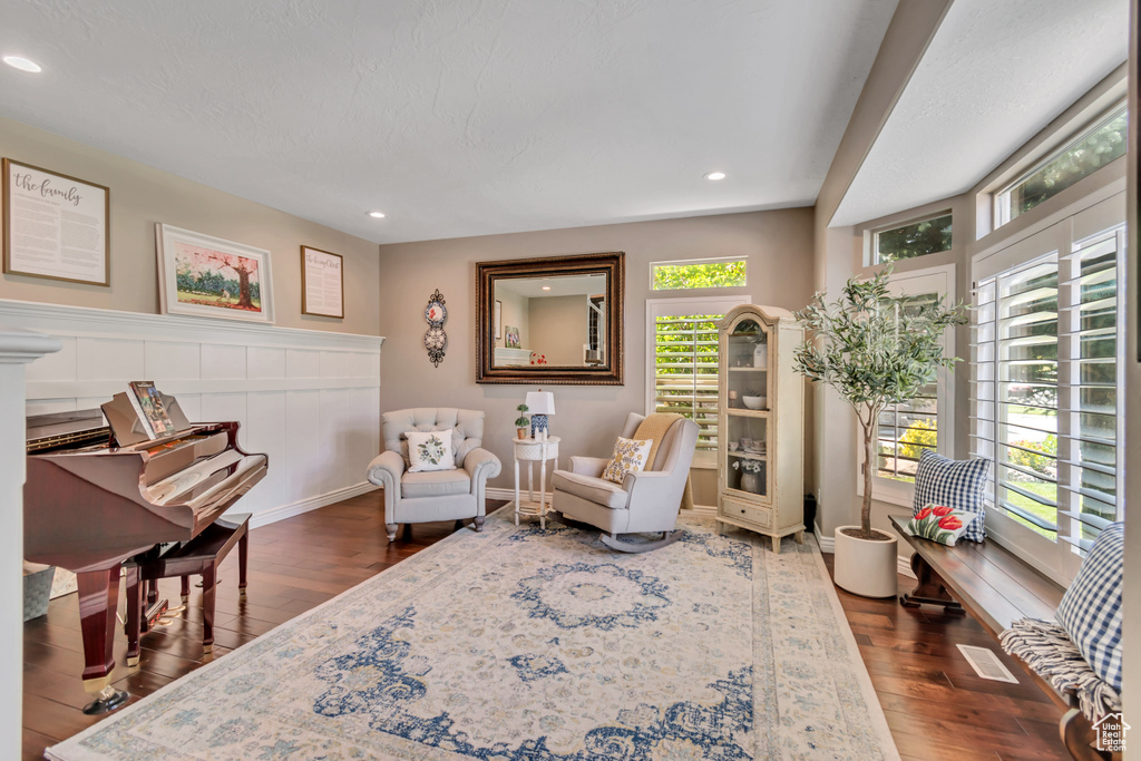 Sitting room featuring dark wood-type flooring, recessed lighting, and wainscoting