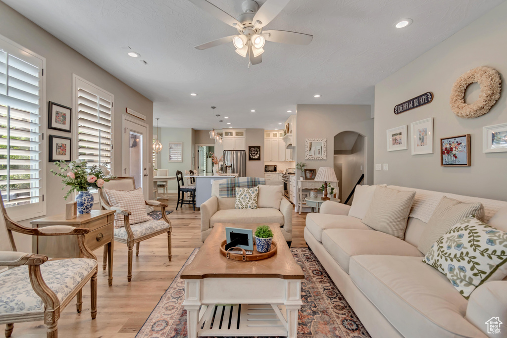 Living room featuring ceiling fan, light wood-style flooring, arched walkways, and recessed lighting