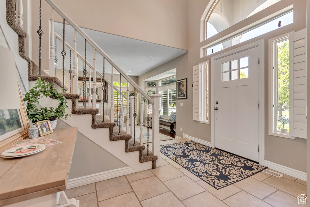 Tiled foyer entrance featuring stairway and healthy amount of natural light
