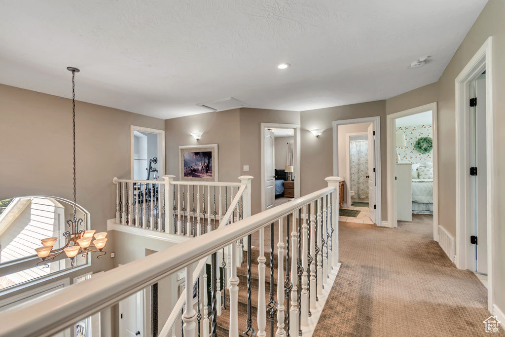 Hall featuring an upstairs landing, a chandelier, light carpet, and recessed lighting