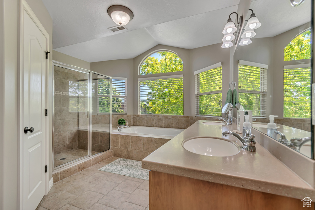 Bathroom featuring healthy amount of natural light, a stall shower, a bath, double vanity, and vaulted ceiling