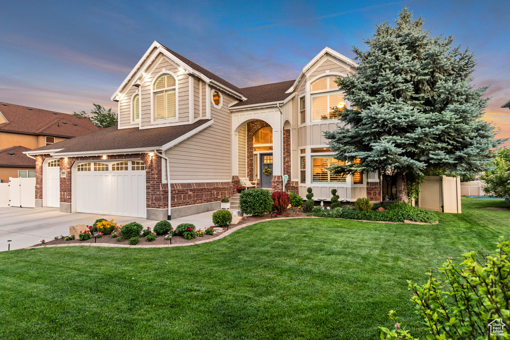 View of front of property with a garage, driveway, a shingled roof, and brick siding