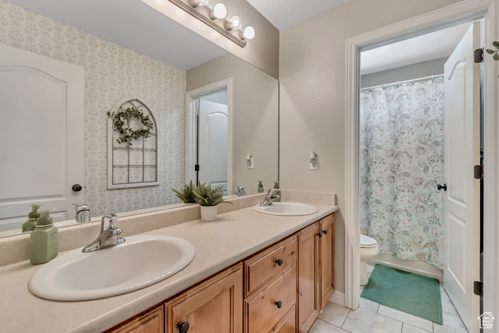 Bathroom with double vanity, tile patterned floors, and curtained shower