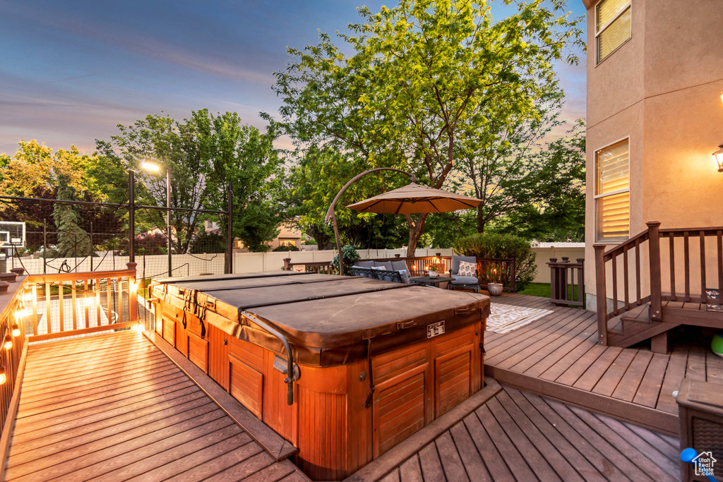 Deck at dusk featuring a covered hot tub