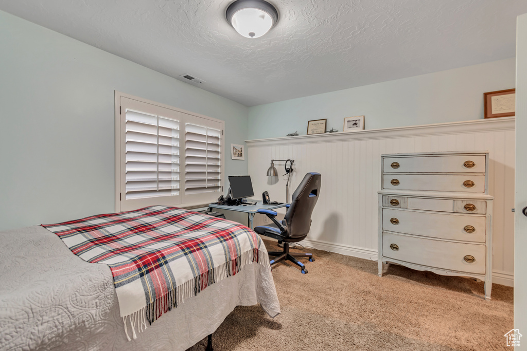 Carpeted bedroom with a textured ceiling and an office area