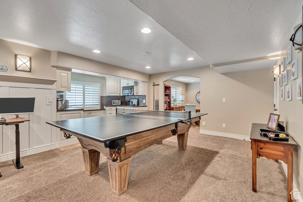 Recreation room with light colored carpet, arched walkways, recessed lighting, and a textured ceiling
