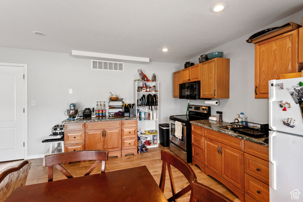 Kitchen featuring freestanding refrigerator, stainless steel range with electric stovetop, black microwave, light wood-type flooring, and recessed lighting