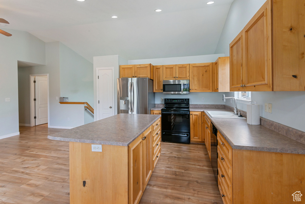 Kitchen featuring black appliances, lofted ceiling, ceiling fan, light wood-type flooring, and a kitchen island