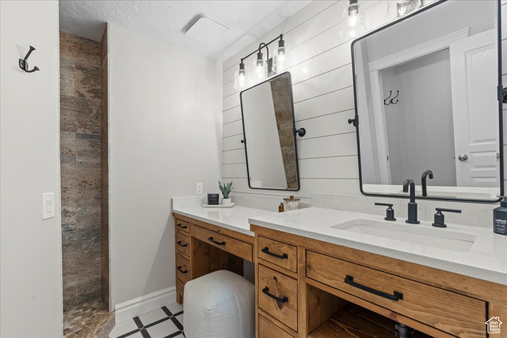Full bath featuring vanity, tile patterned floors, and tiled shower