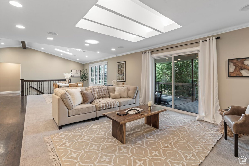 Living room with a skylight, ornamental molding, light wood-style floors, and recessed lighting