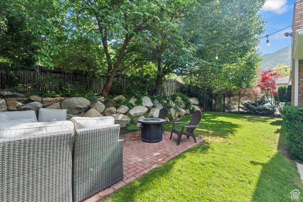 Fenced backyard featuring a patio area, an outdoor living space with a fire pit, and a mountain view