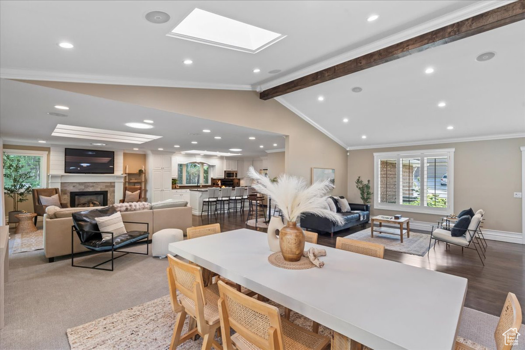 Dining room featuring a large fireplace, crown molding, recessed lighting, and a skylight