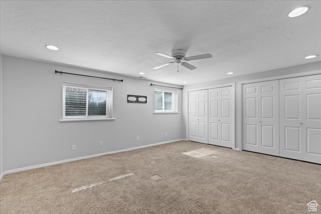 Unfurnished bedroom featuring multiple closets, carpet, recessed lighting, a textured ceiling, and ceiling fan