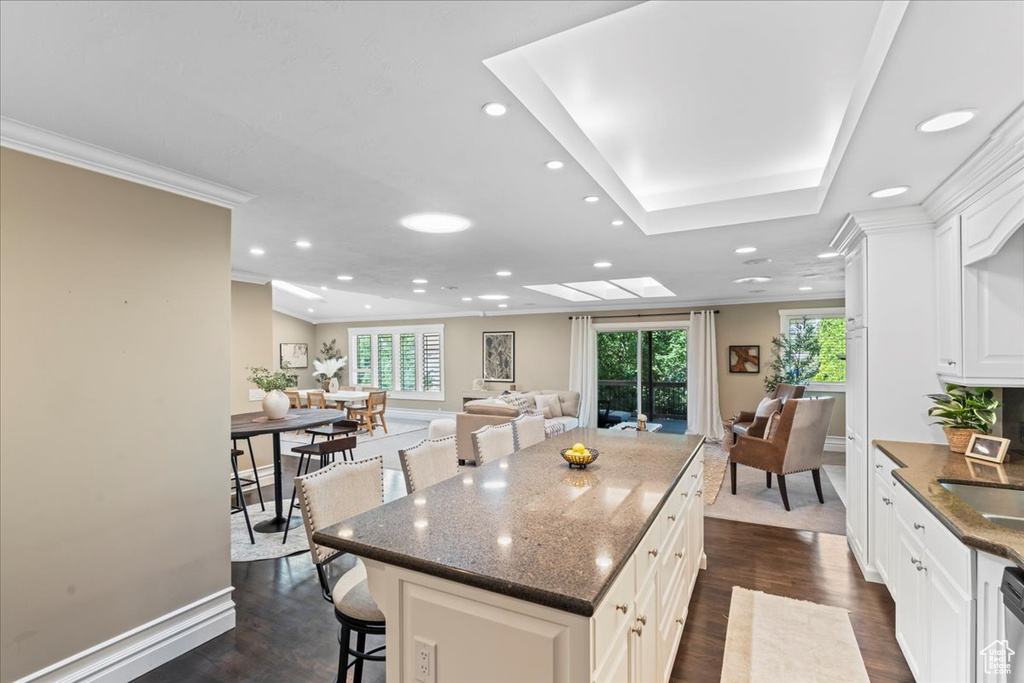 Kitchen featuring a breakfast bar, dark wood-style floors, a center island, recessed lighting, and dark stone countertops