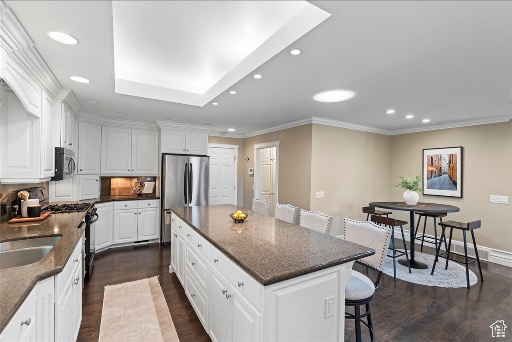 Kitchen with appliances with stainless steel finishes, a breakfast bar area, recessed lighting, a kitchen island, and dark wood-style floors