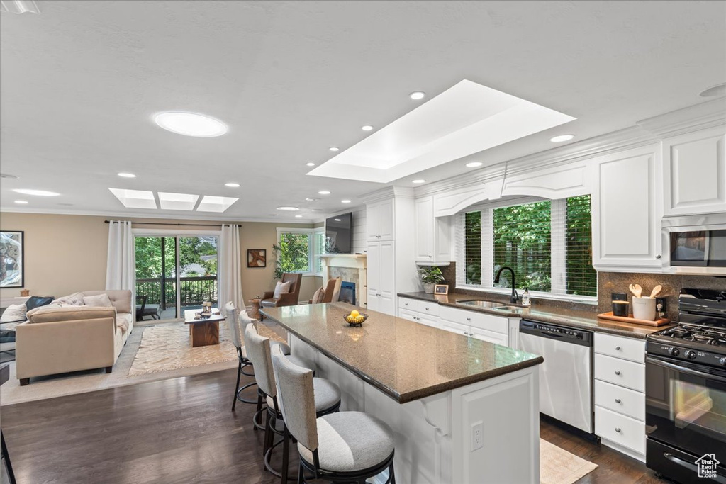 Kitchen with stainless steel appliances, a skylight, open floor plan, recessed lighting, and crown molding