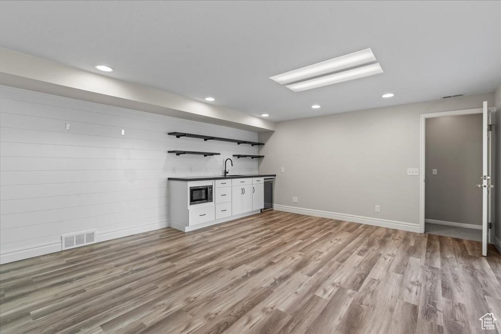 Unfurnished living room featuring bar with sink, light wood-type flooring, and recessed lighting