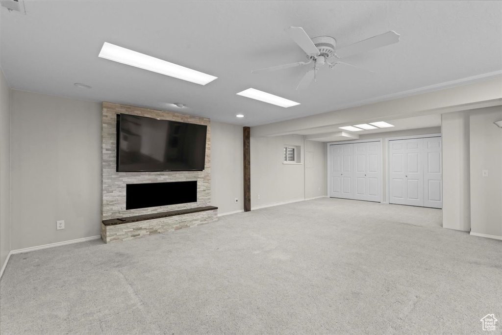 Finished below grade area with a fireplace, carpet floors, and a ceiling fan