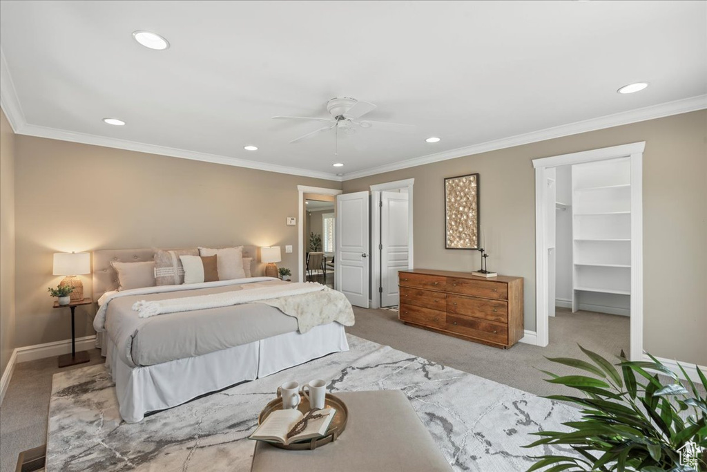 Bedroom with light carpet, recessed lighting, a walk in closet, crown molding, and ceiling fan