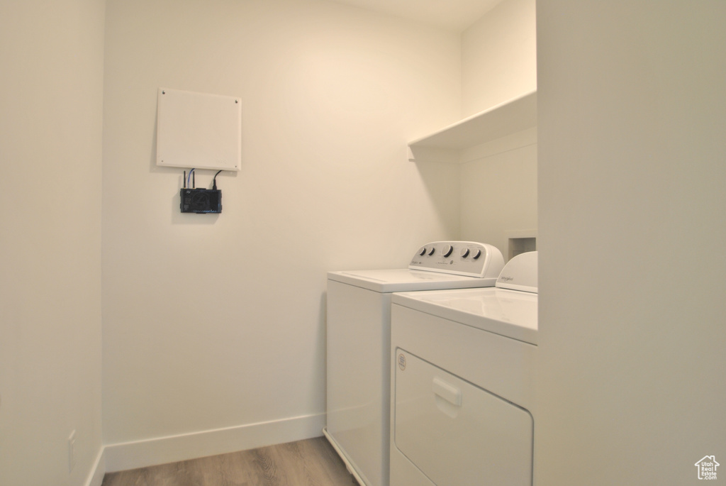 Washroom with washer and dryer and light wood-type flooring