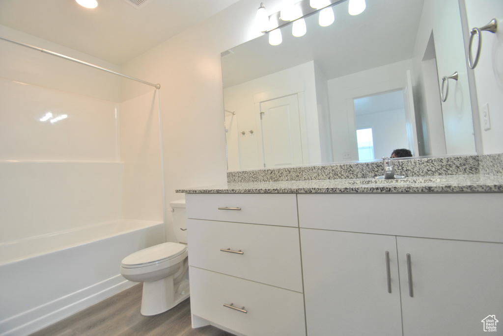 Bathroom featuring wood finished floors, vanity, and tub / shower combination