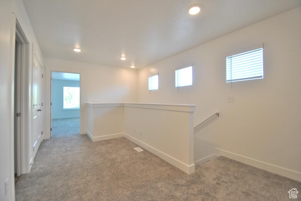 Hall with carpet flooring, an upstairs landing, healthy amount of natural light, and recessed lighting