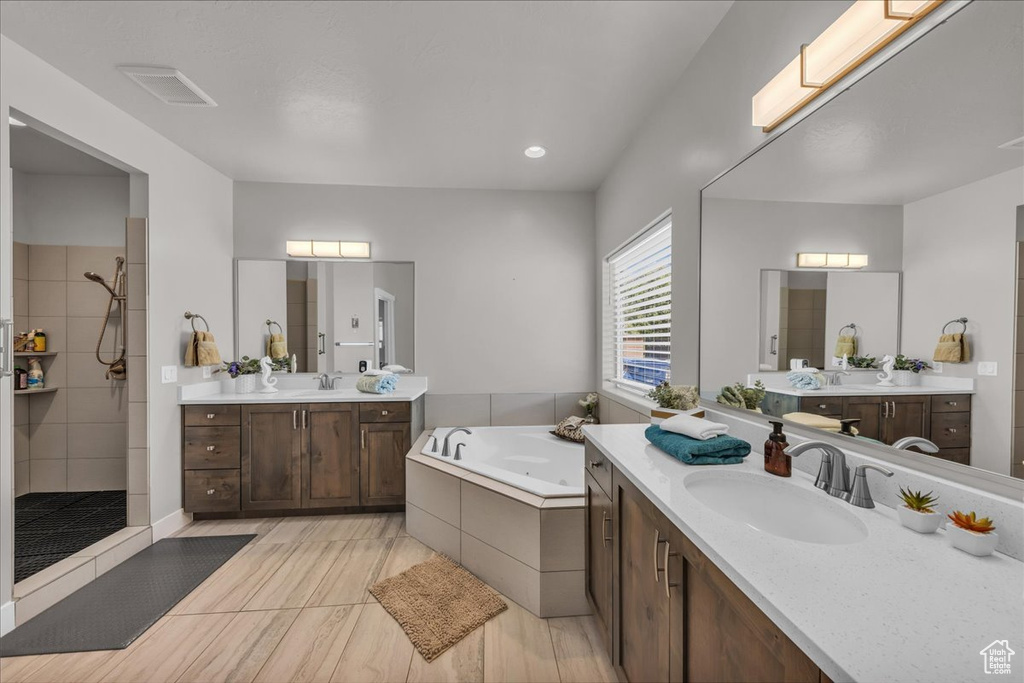 Bathroom featuring a tile shower, two vanities, and a tub with jets