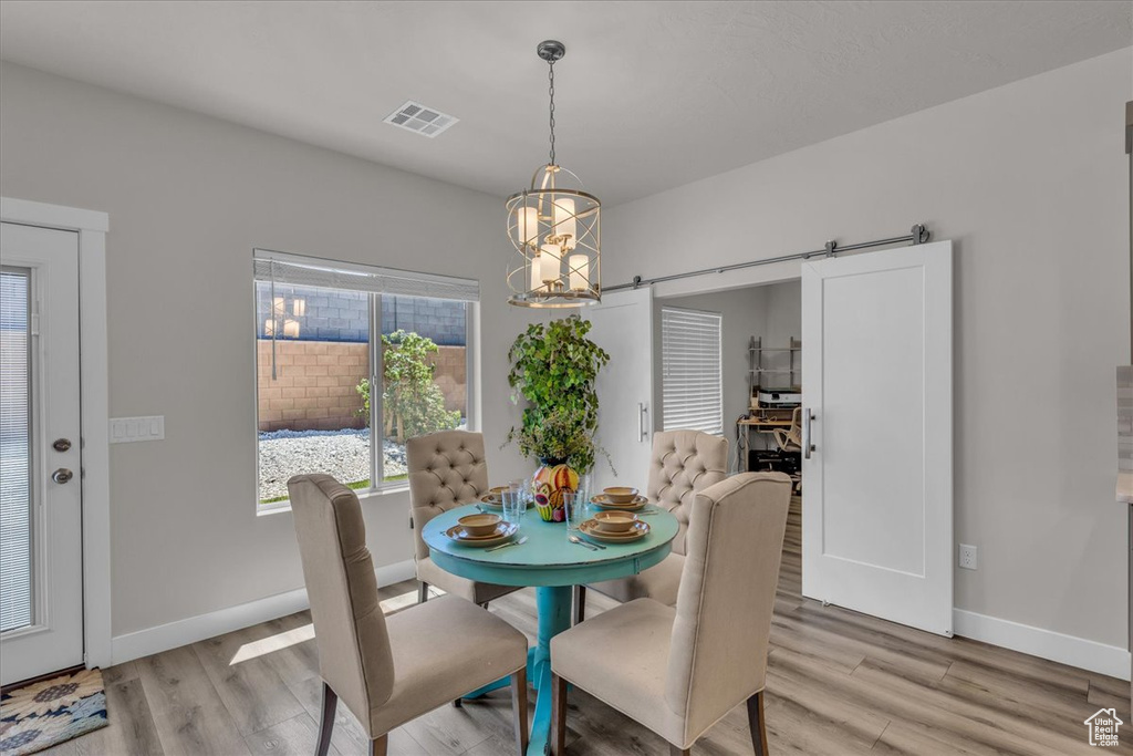 Dining room with a chandelier, a barn door, and light wood-style flooring