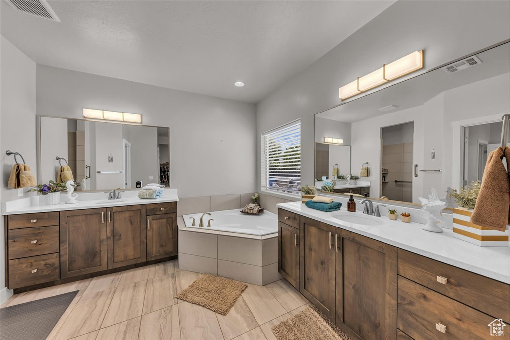 Full bath featuring two vanities and a garden tub