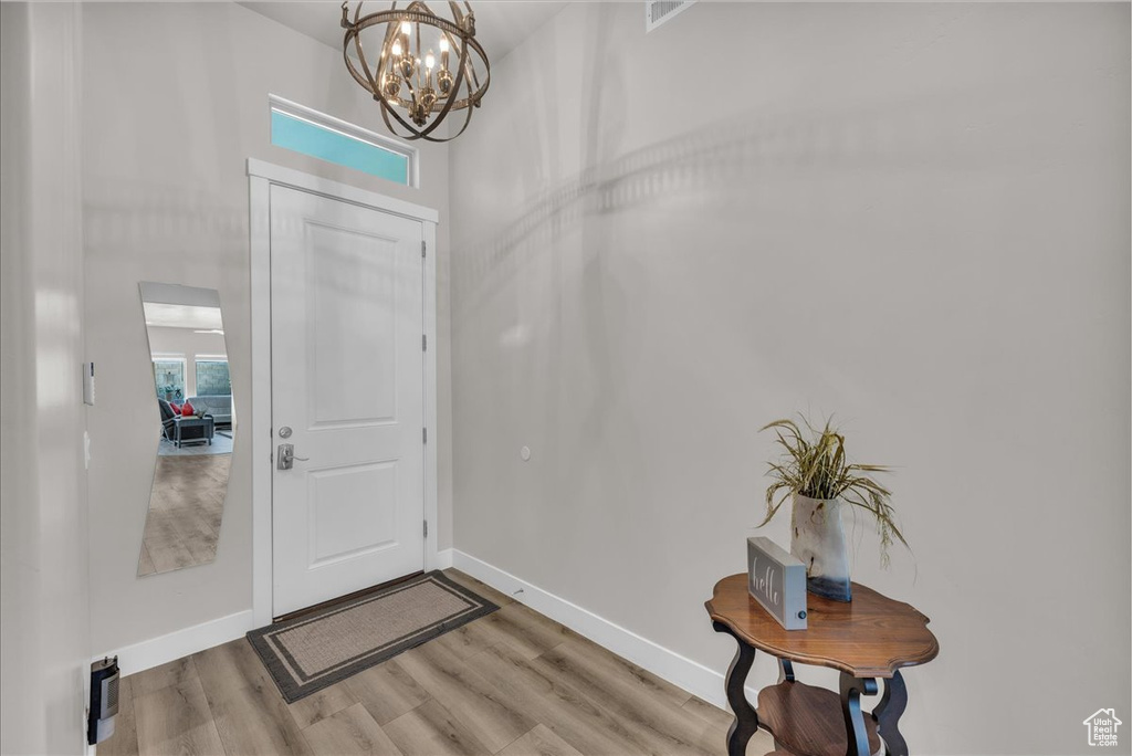 Foyer featuring light wood finished floors and a chandelier