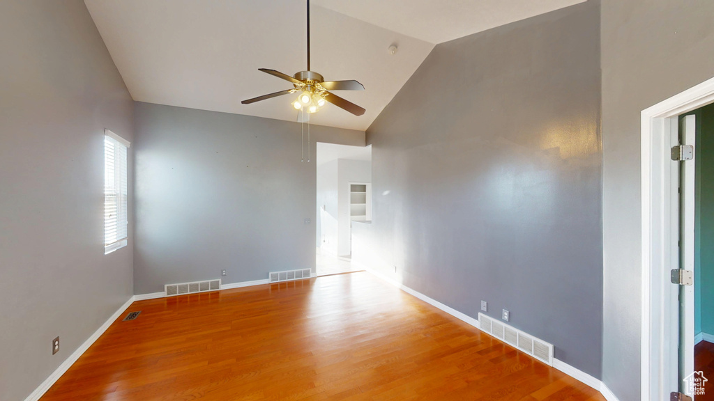 Empty room featuring a ceiling fan, wood finished floors, and high vaulted ceiling