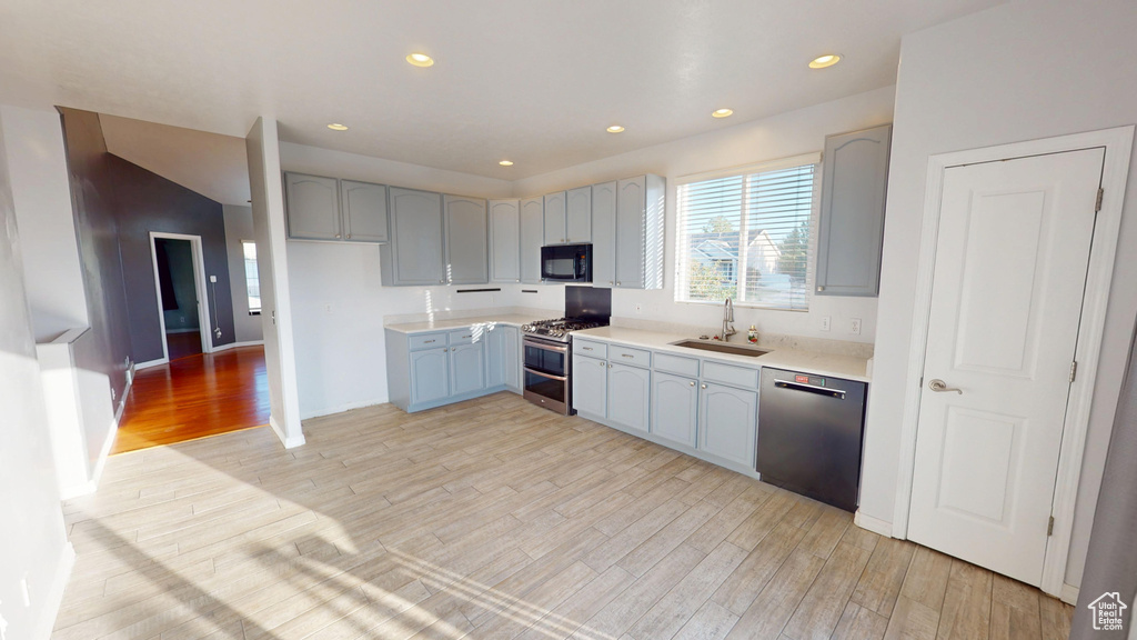 Kitchen featuring range with two ovens, dishwashing machine, black microwave, light wood-style flooring, and recessed lighting