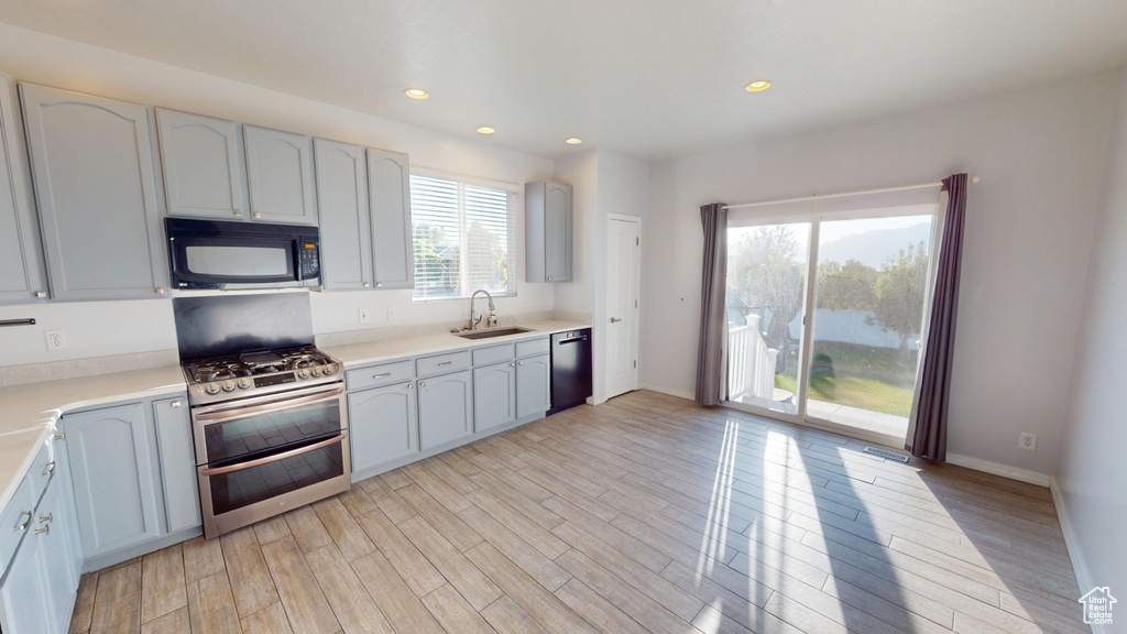 Kitchen featuring black microwave, double oven range, dishwashing machine, light wood-style flooring, and recessed lighting