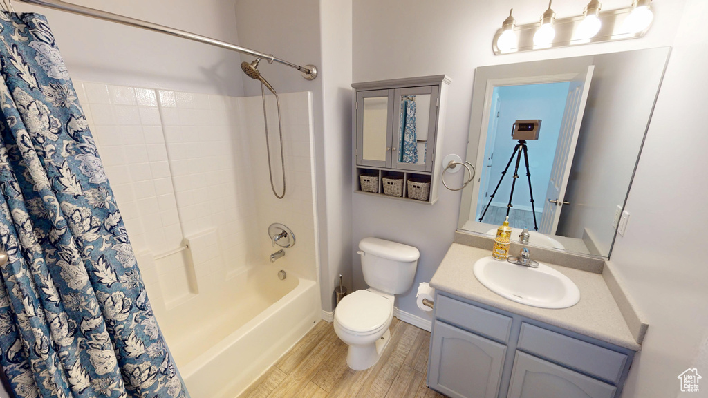 Bathroom featuring vanity, shower / tub combo, and wood finished floors