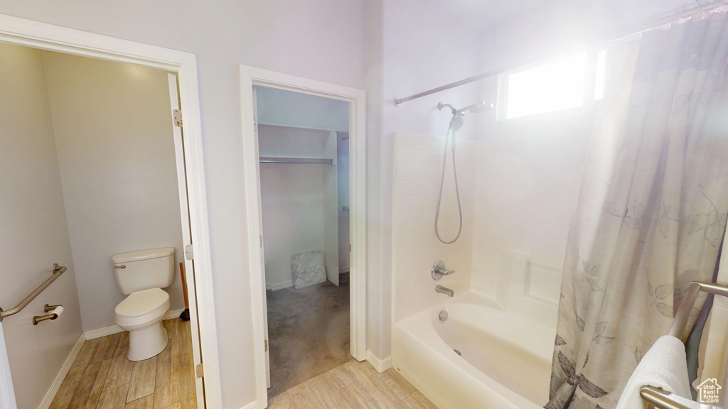 Bathroom featuring shower / bath combination with curtain and wood finished floors