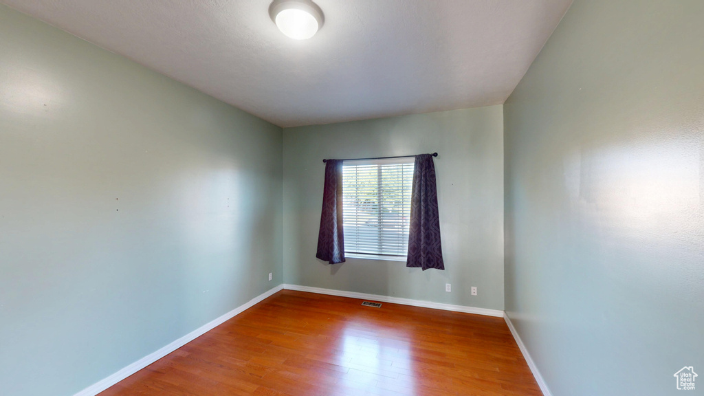 Unfurnished room with wood finished floors and baseboards