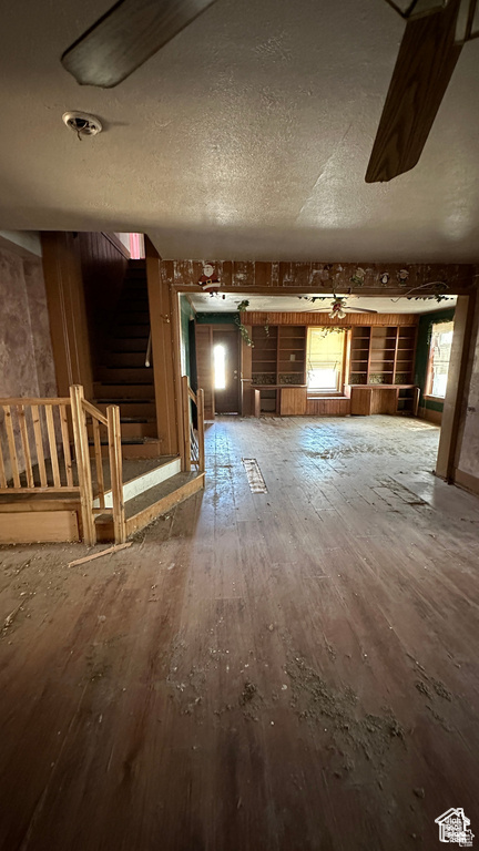 Unfurnished living room with wood-type flooring, stairway, and a textured ceiling