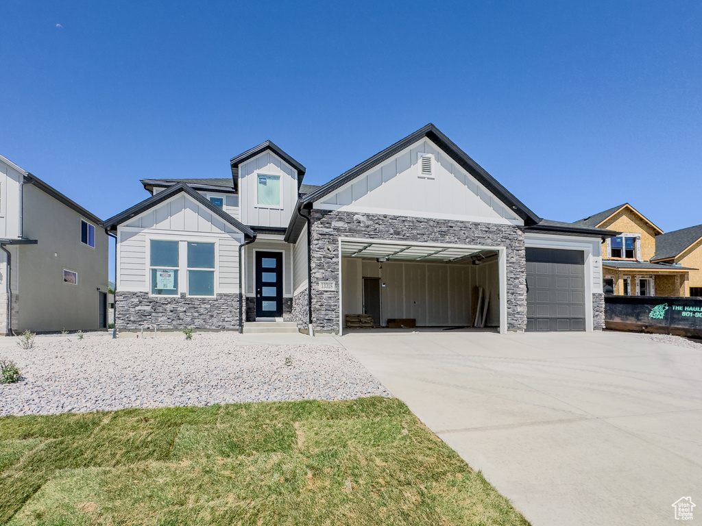 View of front of house featuring board and batten siding, stone siding, an attached garage, and concrete driveway