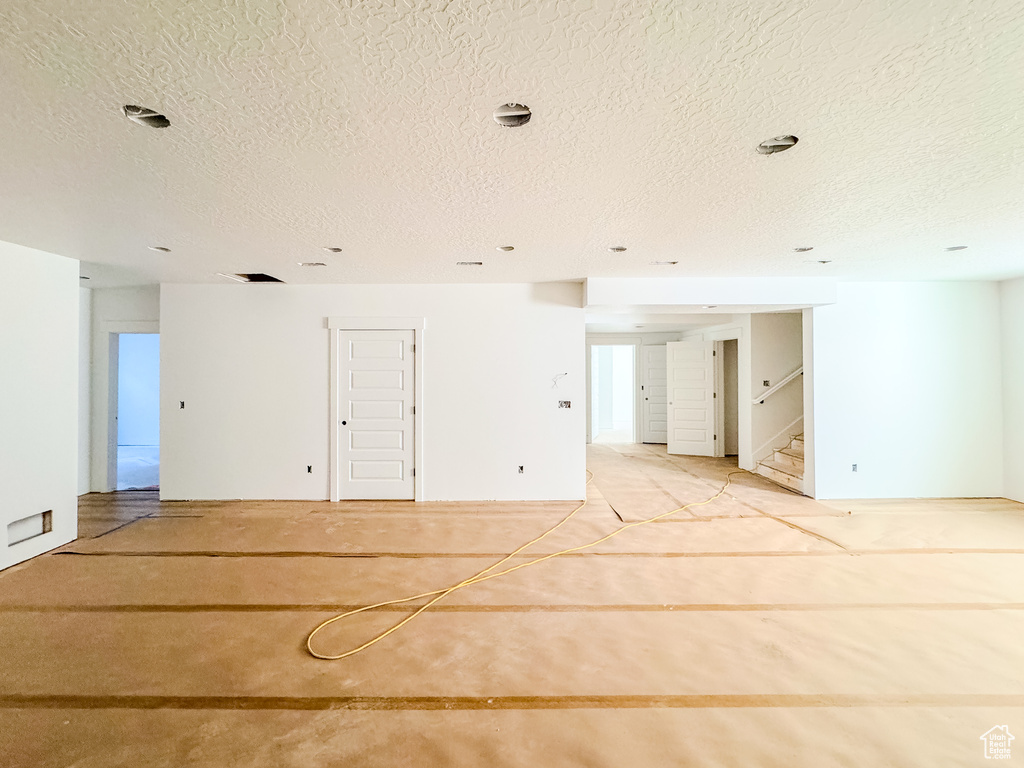 Unfurnished room featuring a textured ceiling and stairs