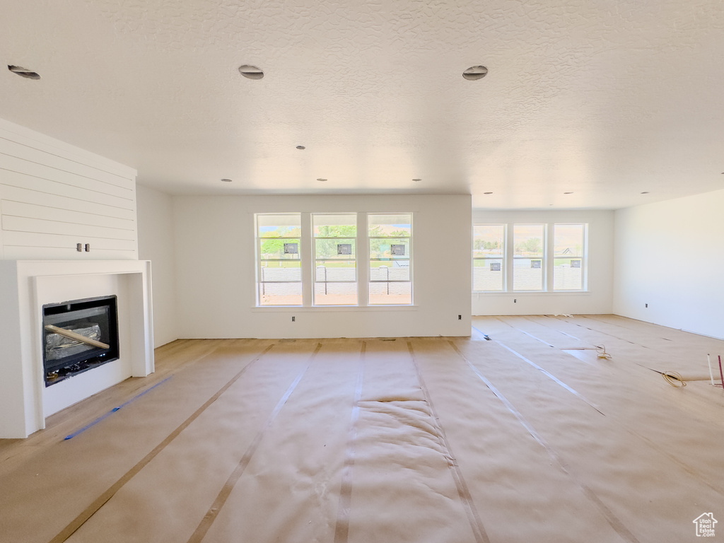 Unfurnished living room featuring a glass covered fireplace and healthy amount of natural light